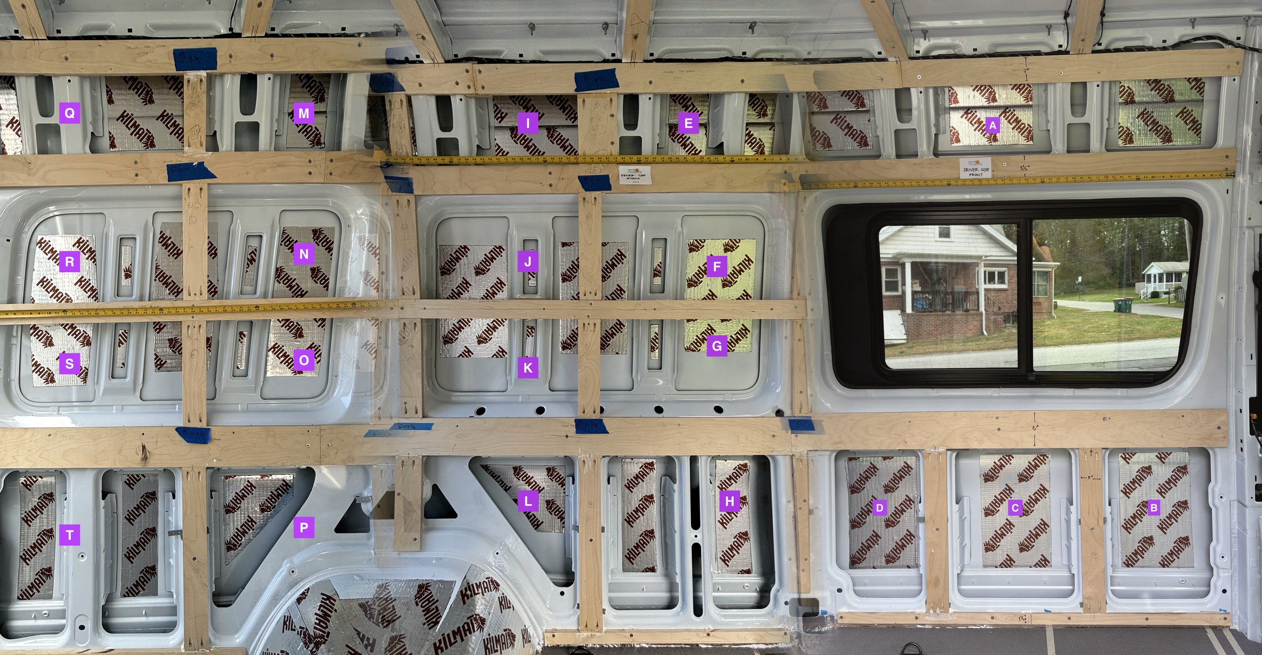 Driver-side van wall, stitched panorama, with each cavity labeled with its wire-pull letter code from A through T.